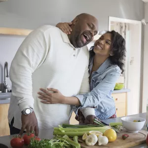 A couple shares a sweet moment as they prepare vegetables in their kitchen